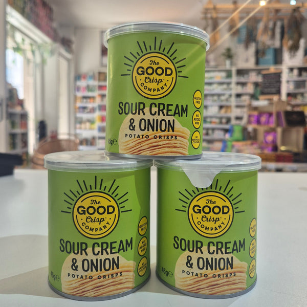 Three cans of Good & Gather Sour Cream & Onion potato chips on a reflective surface with a store interior in the background.