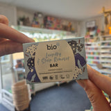 Hand holding a bio-d laundry and stain remover bar in a store setting