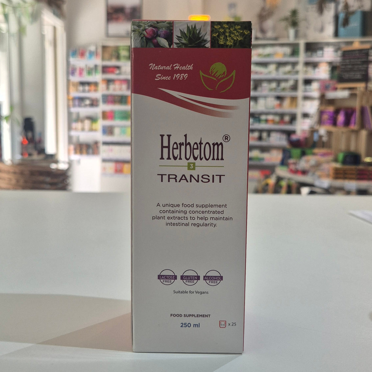 A 250 ml box of Herbetom Transit food supplement standing upright on a white counter with a blurred store background.