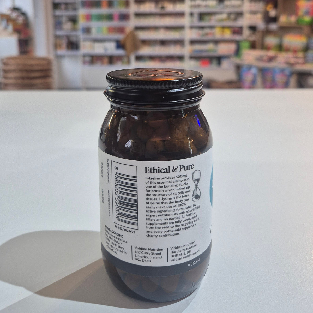 Bottle of Viridian L-Lysine supplement on a white surface with a blurred background