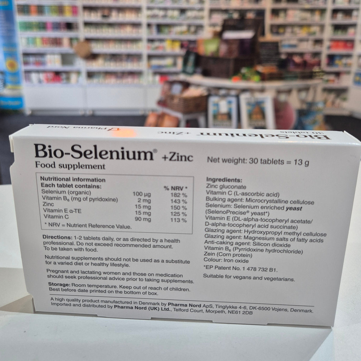 Supplement box labeled 'Bio Selenium + Zinc' on a counter with a blurred store background.