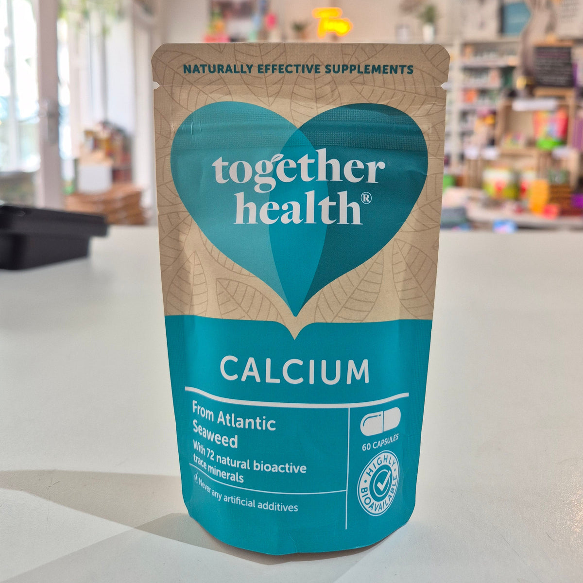 Packaging of Together Health Calcium supplements with a clear window showing the tablets inside. The package is predominantly blue and white with a heart shape design.