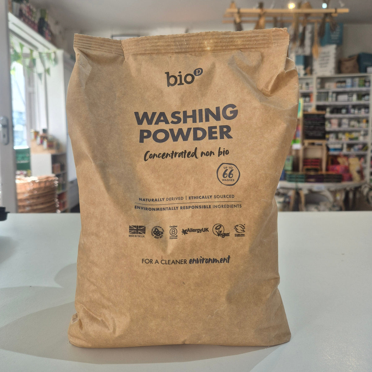 Paper bag of washing powder with visible branding on a white surface.