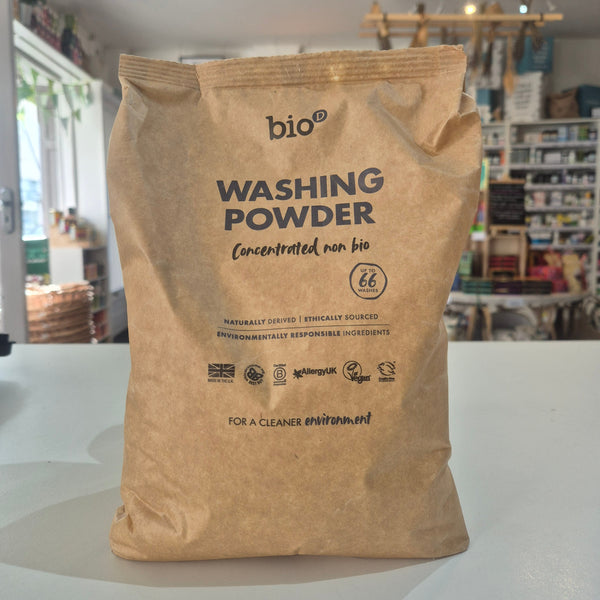Paper bag of washing powder with visible branding on a white surface.