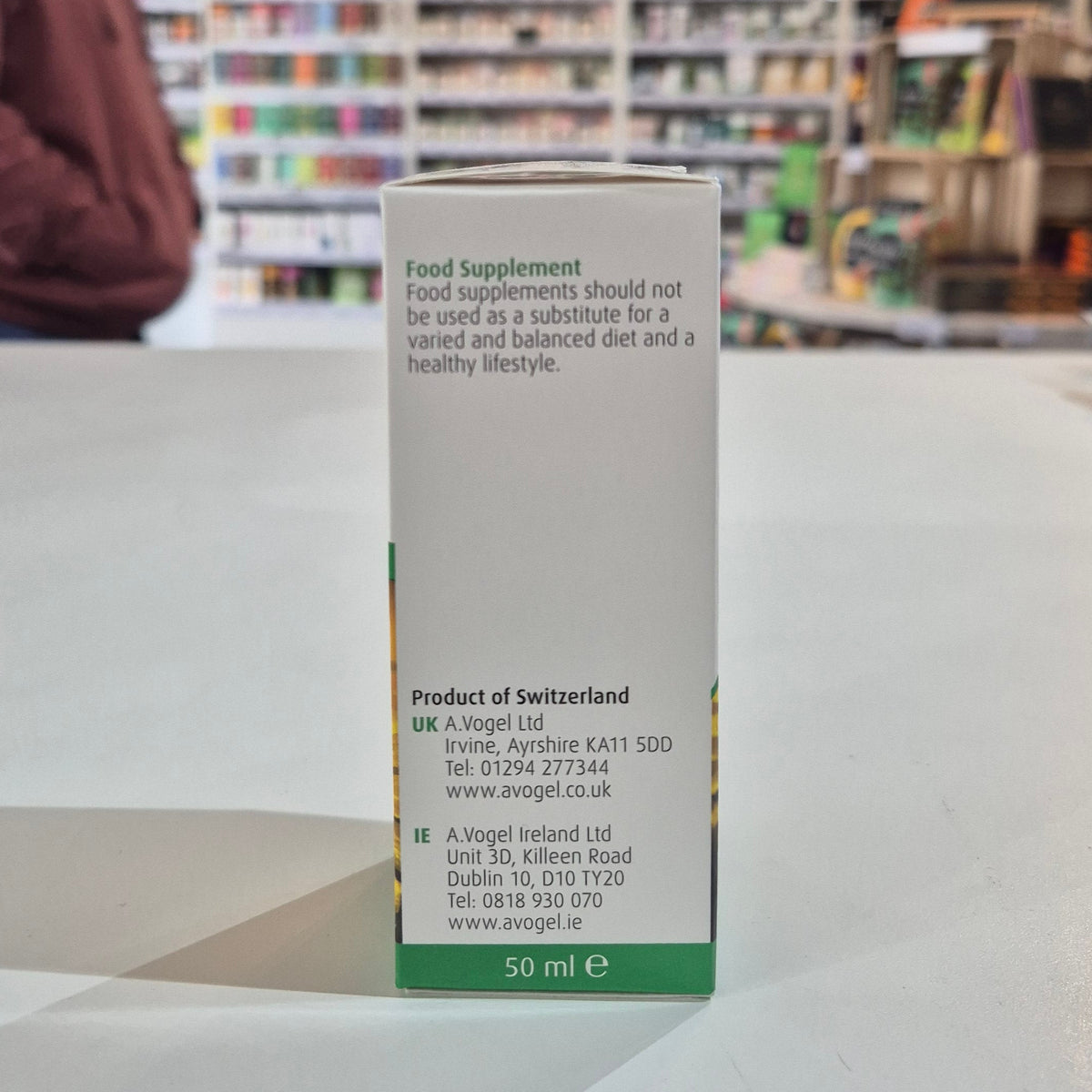 Box of a food supplement with text on a table in a store setting