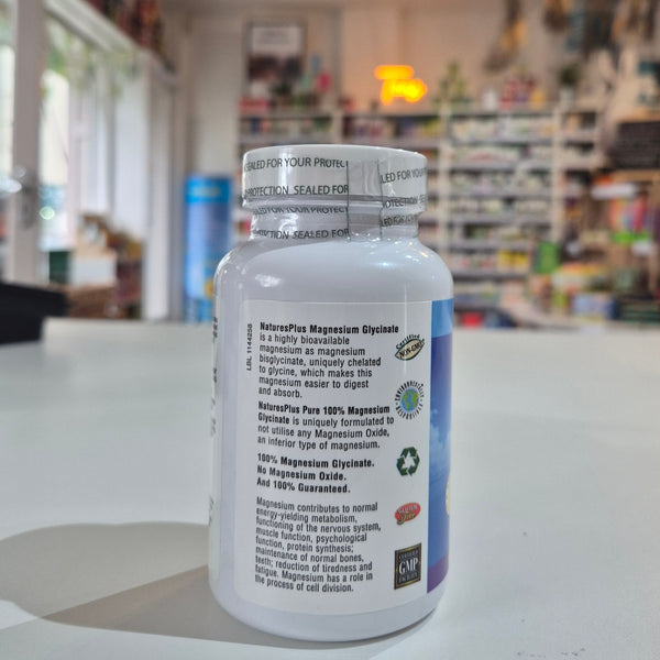 Supplement bottle with label on a counter in a store setting. A bottle of Nature's Plus Magnesium Glycinate supplement with 90 capsules, labeled for supporting cardiovascular health, nerve & muscle relaxation, and overall psychology function.