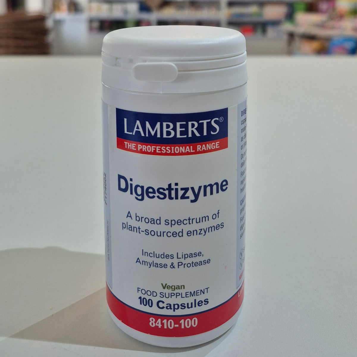 Lamberts Digestizyme supplement container on a white surface with a blurred background