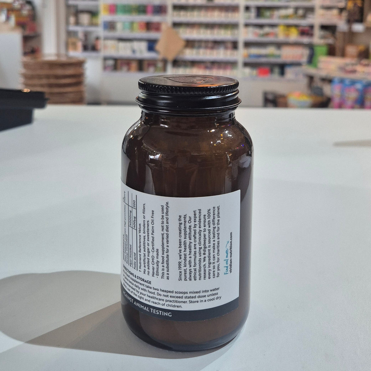 Myo-Inositol & Folic supplement bottle with Viridian label on a white surface, with  blurred store interior in the background