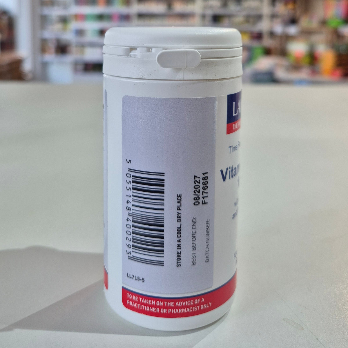 White supplement container with label on a white surface, blurred background