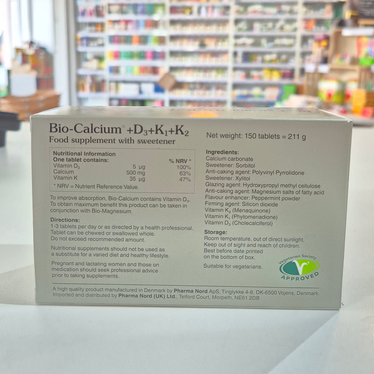 Box of Pharma Nord Bio Calcium + D3 - 150 Tabs with tablets displayed in front. Product packaging with text and a logo on a shelf in a store setting