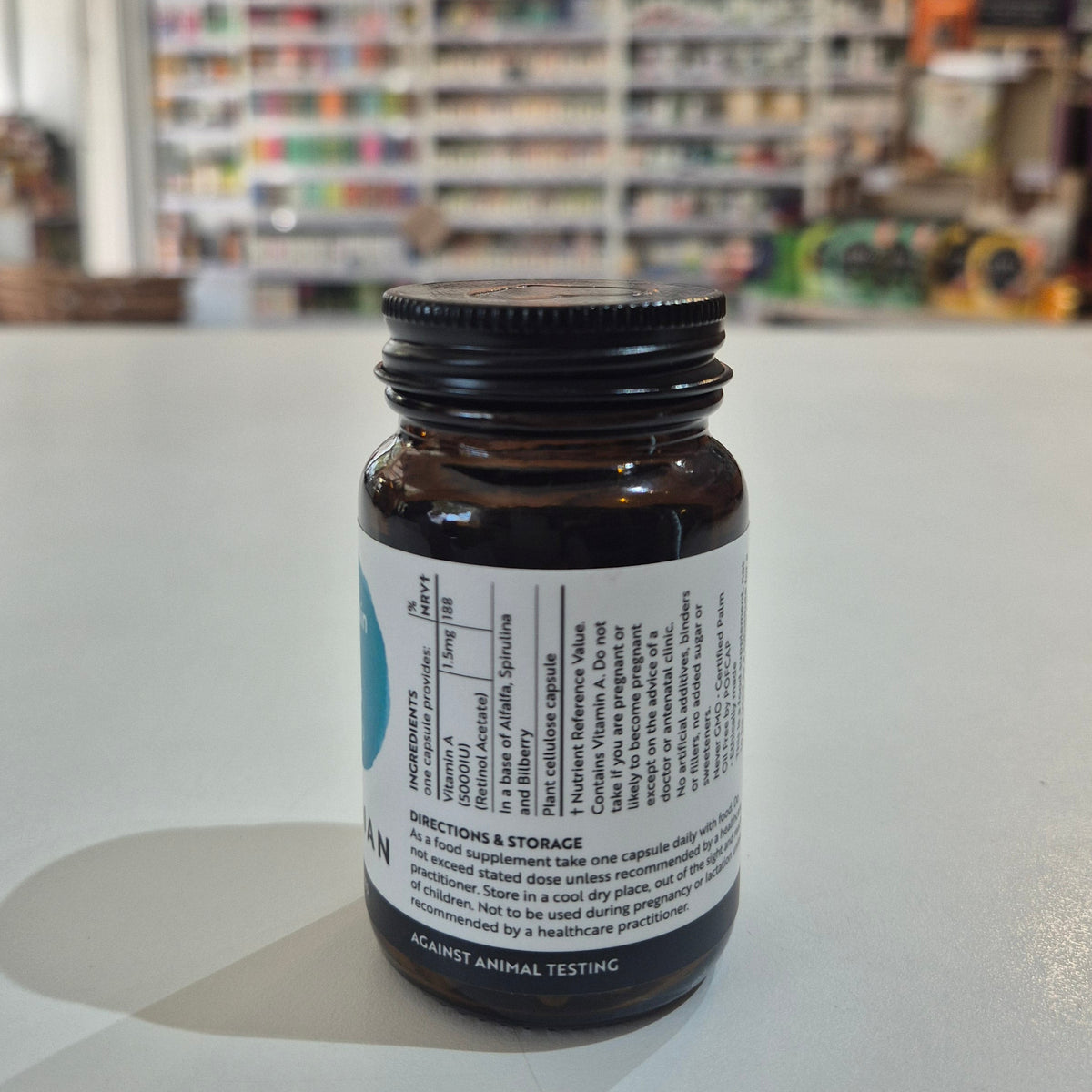 Brown supplement bottle with label on a white surface, blurred store background