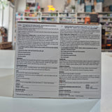 Back of a product box with text and branding, blurred indoor background
