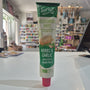 A tube of Tartex Vegetarian Pate Herbs & Garlic spread lying horizontally on a white surface, with a blurred store interior in the background.