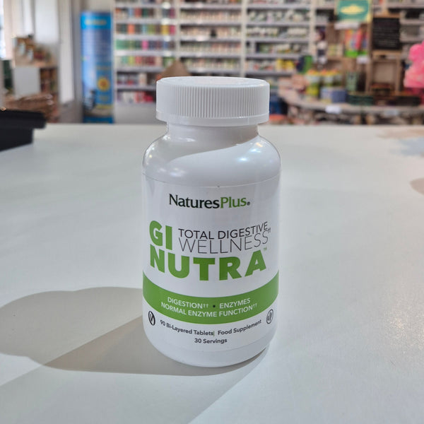 NaturesPlus GI Nutra supplement bottle on a white surface with a blurred store background