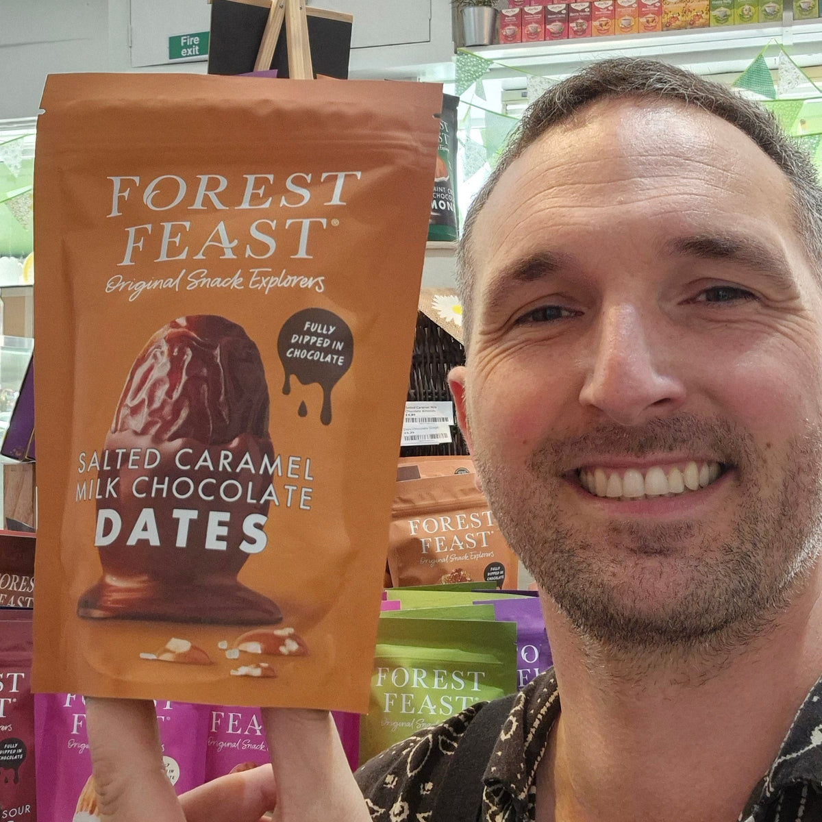 Person holding a package of Forest Feast salted caramel milk chocolate dates in a store setting.
