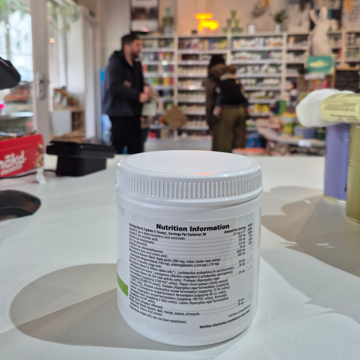 Close-up of a supplement container with a blurred store interior in the background