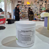 Close-up of a supplement container with a blurred store interior in the background