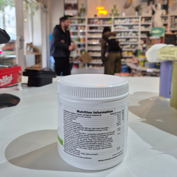 Close-up of a supplement container with a blurred store interior in the background