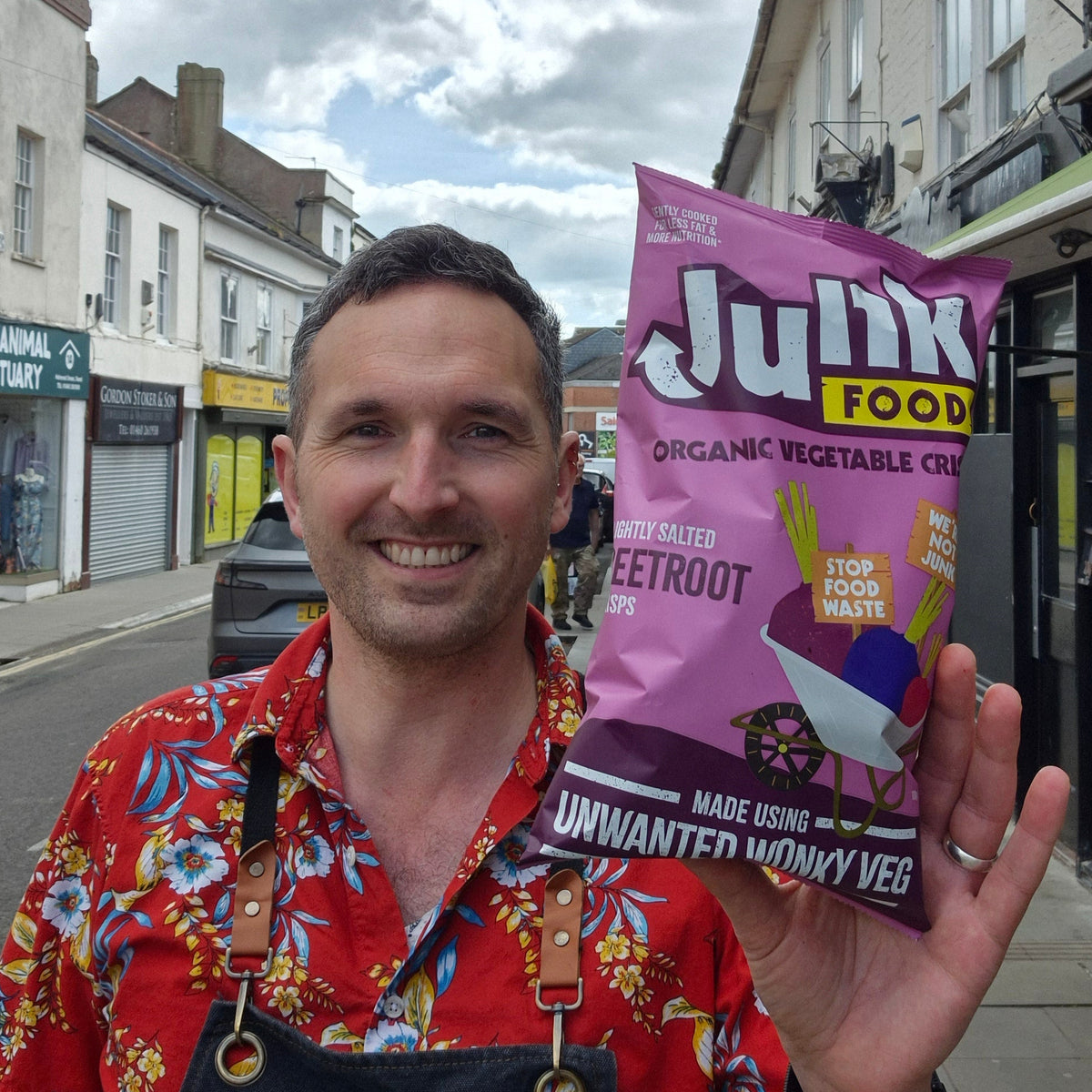 Man holding a purple 'Junk Food' package on a street
