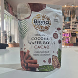 Packaging of Biona Organic Coconut Wafer Rolls Cacao on a white surface with a blurred indoor background.