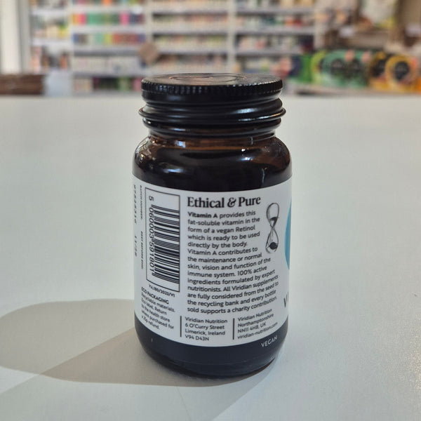 Brown supplement bottle with label on a white surface, blurred store background