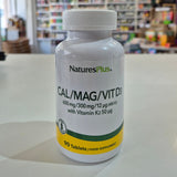 NaturesPlus Cal/Mag/Vit D3 supplement bottle on a table with a blurred store background