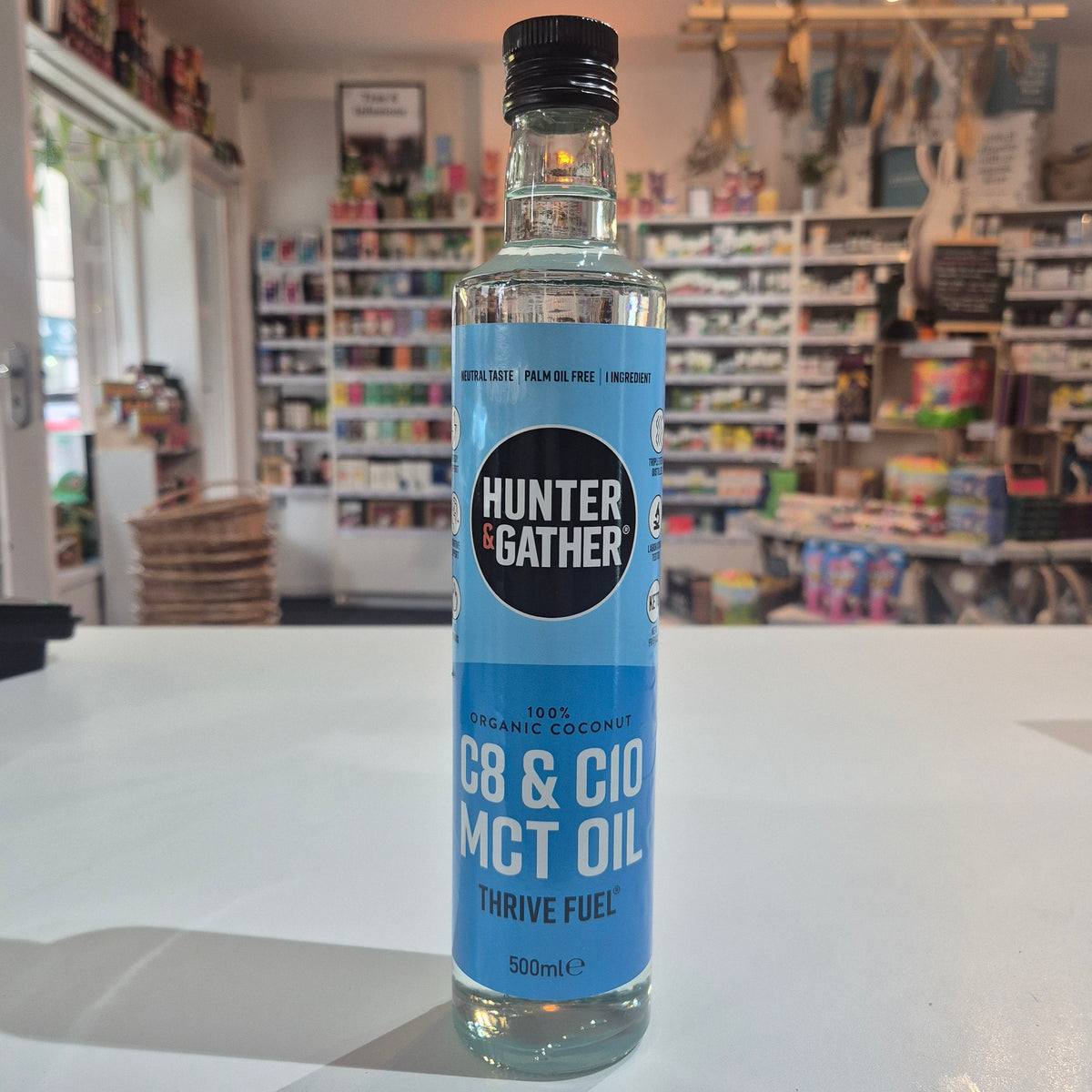 Bottle of Hunter Gatherer MCT oil on a white surface with a blurred store background