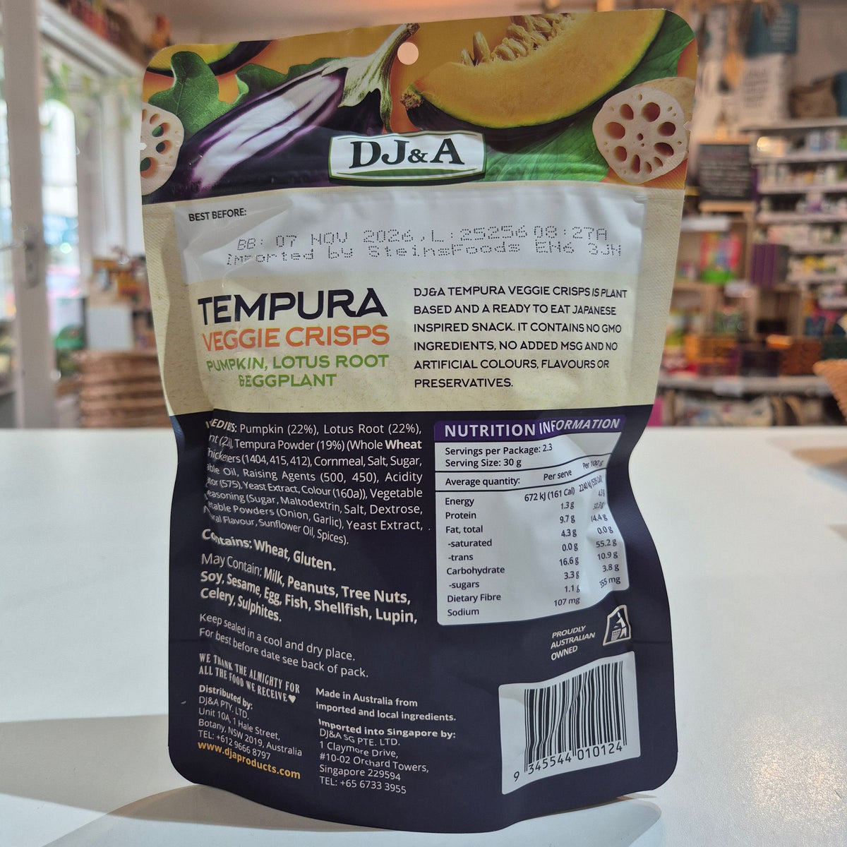 Packaging of DJ&A Tempura Veggie Crisps with ingredients and nutrition information on a blurred background.