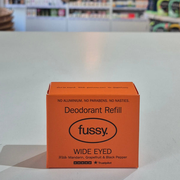 Orange 'fussy' deodorant refill box on a white surface with a blurred background