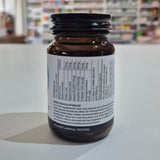 Supplement bottle with label on a white surface, blurred background
