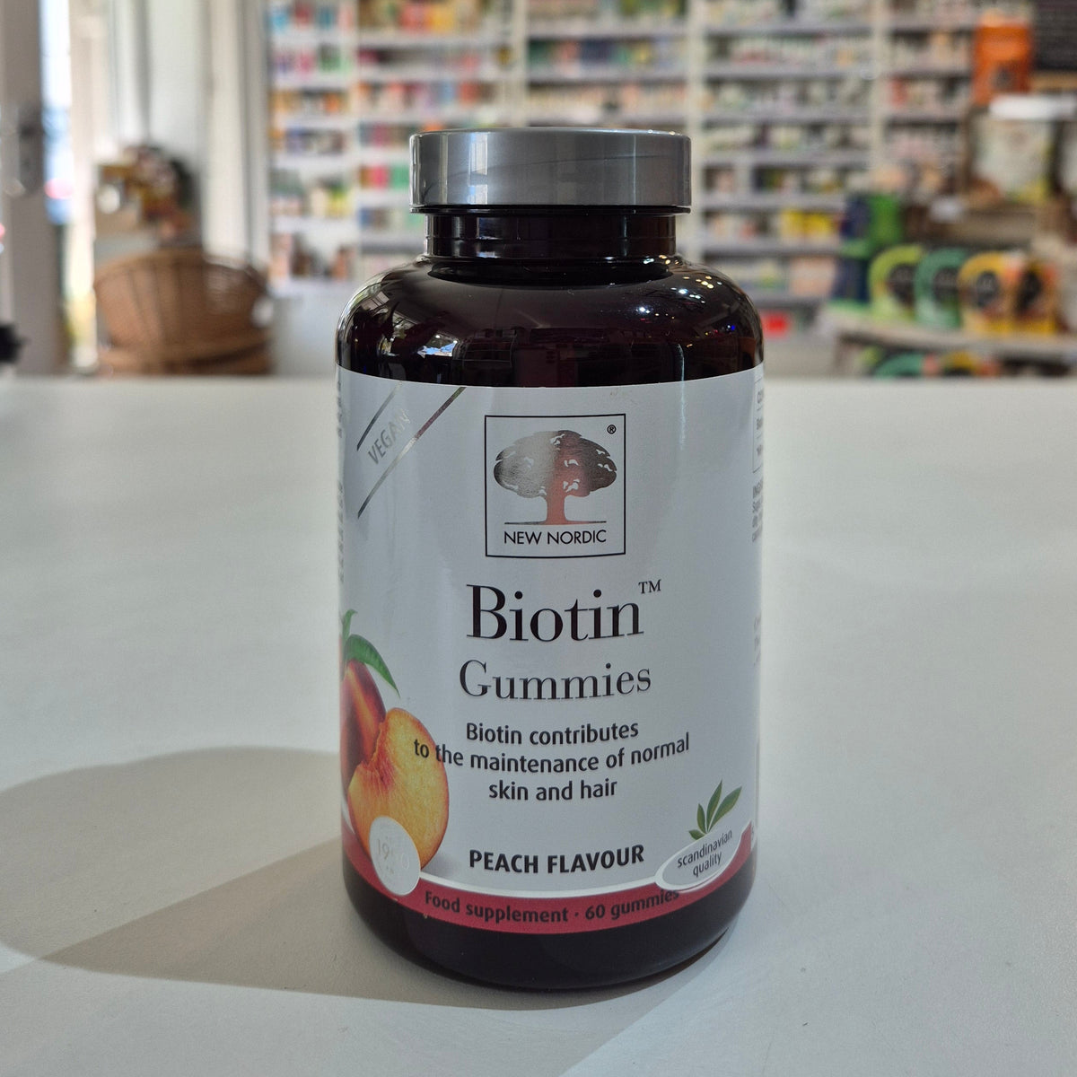 Bottle of New Nordic Biotin Gummies with peach flavor label on a counter.
