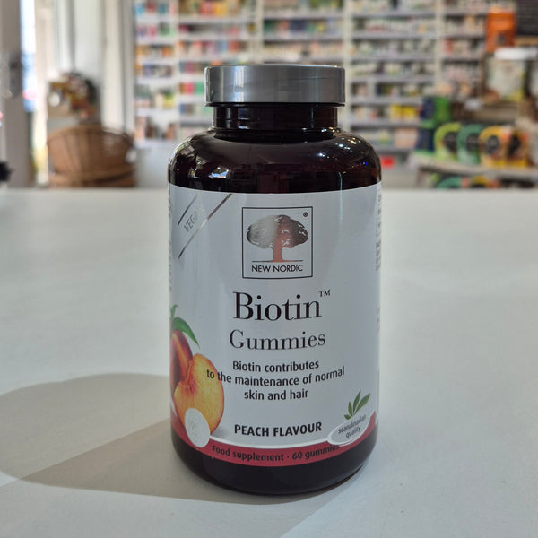 Bottle of New Nordic Biotin Gummies with peach flavor label on a counter.