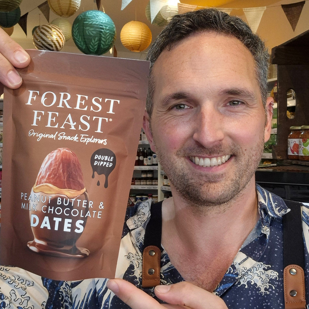 Man holding a 'Forest Feast' snack package in a store setting