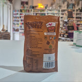 A brown bag of Mummy Meegz treats standing upright on a white counter in a blurred health store setting.