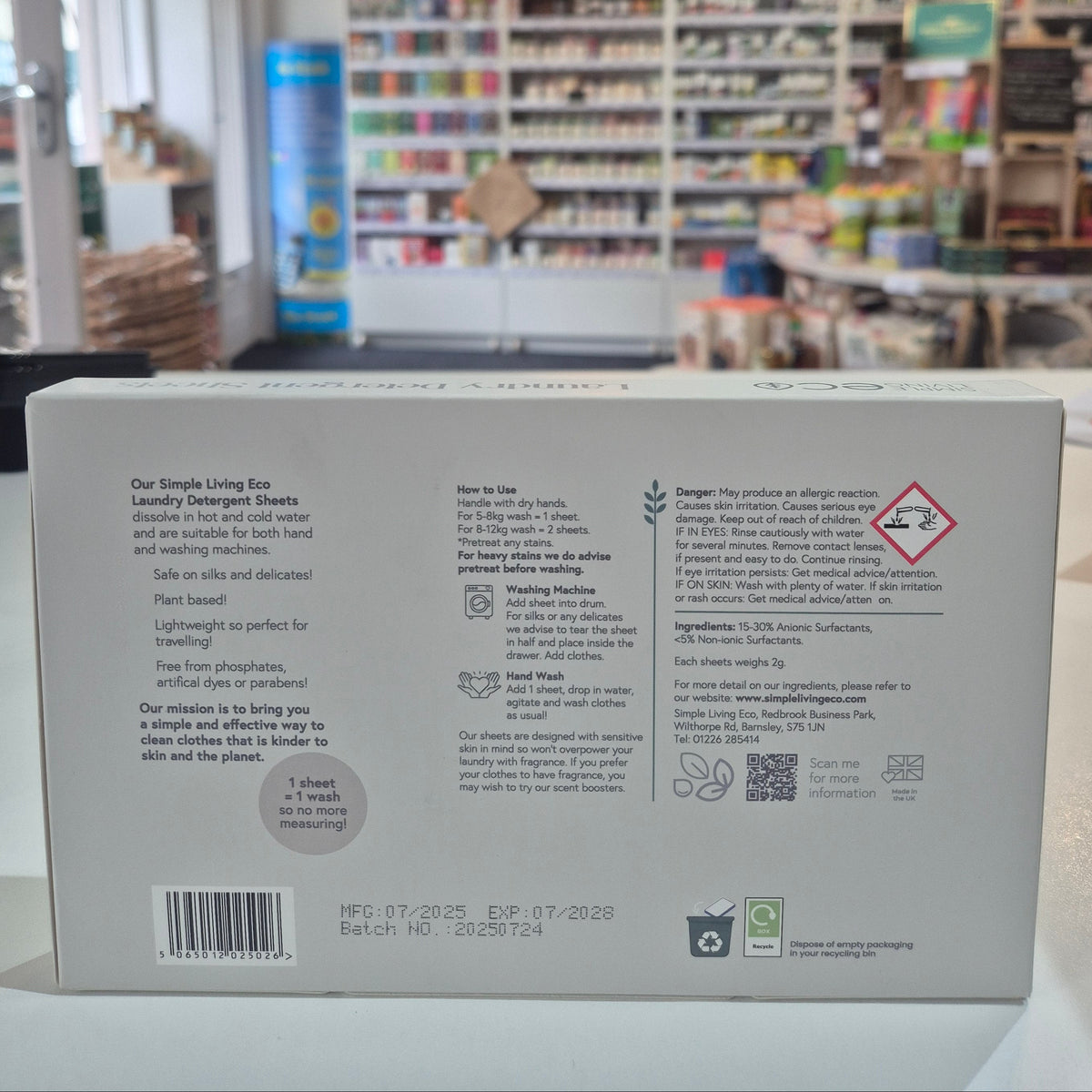 Product packaging with text and symbols on a blurred bookshelf background