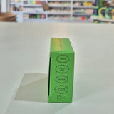 Green product box with certification labels on a white surface, blurred store background